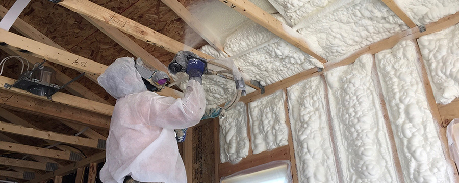 Worker applying spray foam insulation to wall